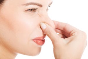 Woman pinching nose from bad odor.