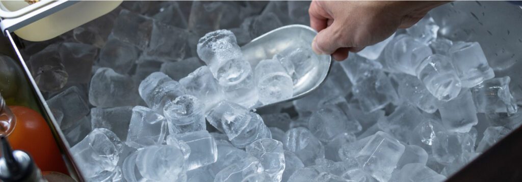 hand scooping ice out of a commercial ice maker